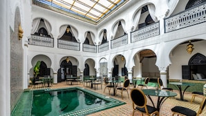 A luxurious indoor pool area with multiple seating arrangements and a high ceiling with intricate designs. - The Grand Riad & Spa  (Marrakech)