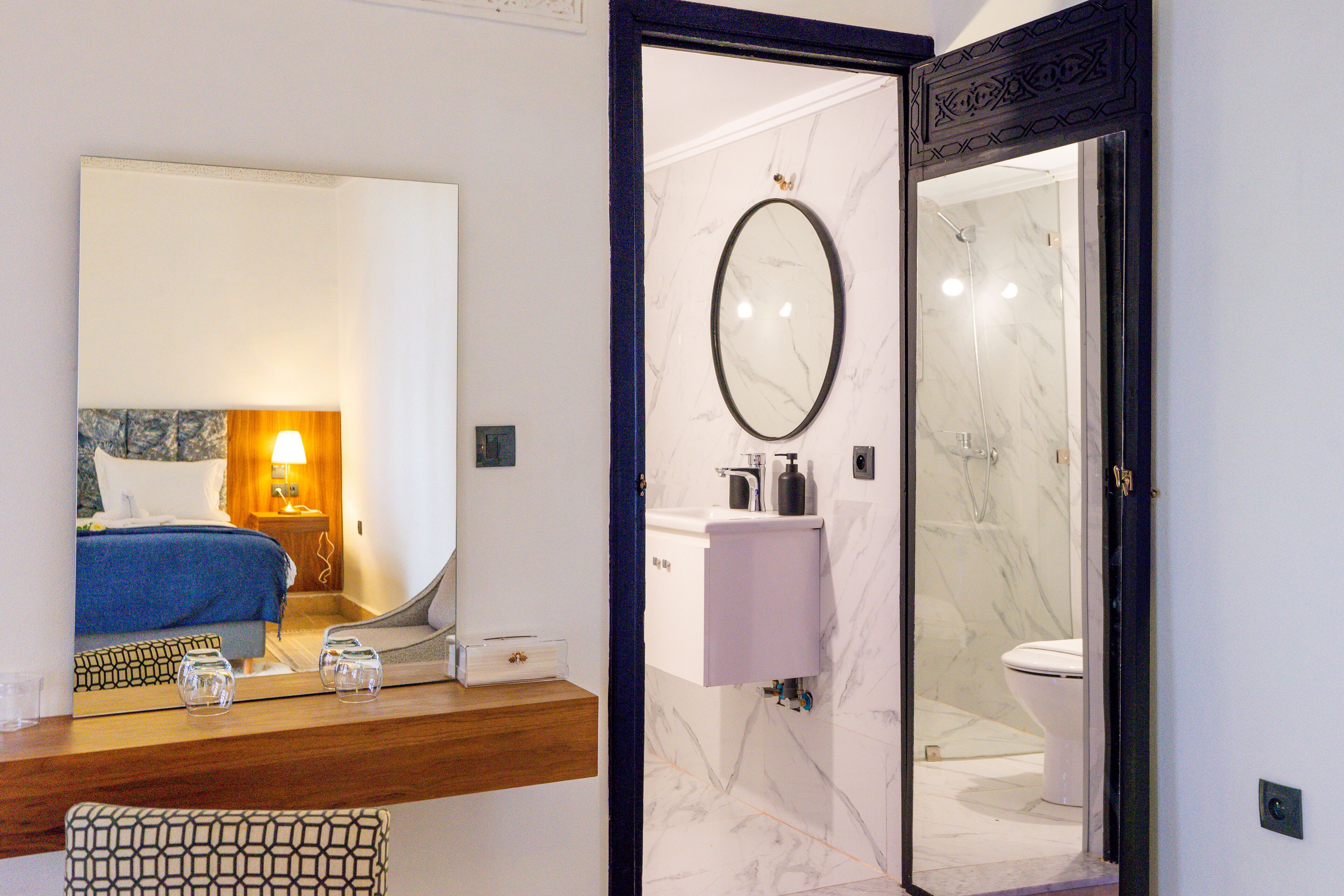Een hotelbadkamer met een marmeren wastafel, een spiegel en een douche.