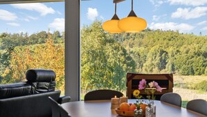 A dining area with a table set for four, a sofa, and a view of a forested hillside. - "Merja" - 3km from the sea by Interhome (Ebeltoft)