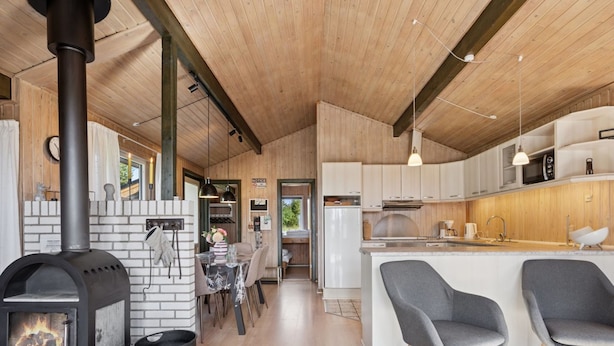 A modern kitchen with a central island, a wood-burning stove, and a dining area with a table and chairs.