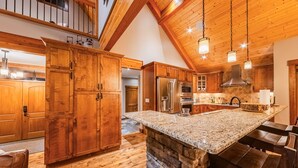 A spacious kitchen with wooden cabinets, granite countertops, and a stone island. - Upscale 4BR mountain retreat with private hot tub, AC, and Mountain Club access. (Kimberley)