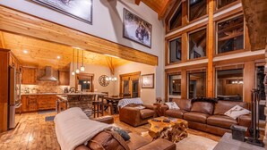 A spacious living area with a large brown leather sofa, a wooden coffee table, and a stone fireplace. - Upscale 4BR mountain retreat with private hot tub, AC, and Mountain Club access. (Kimberley)