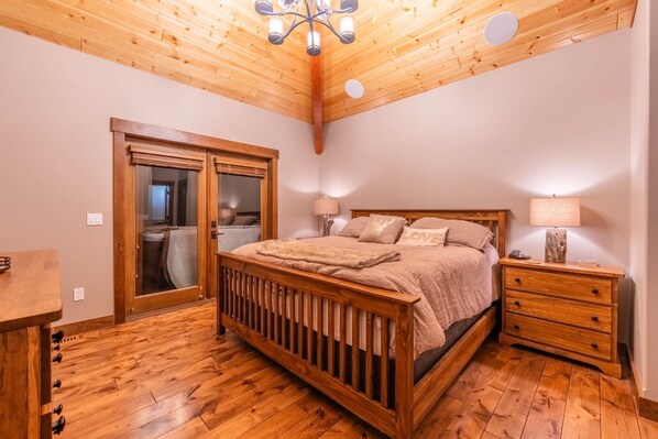 A bedroom with a wooden bed, bedside tables, and a wooden ceiling.