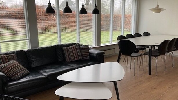 A modern living room with a black leather sofa, a white coffee table, and a dining area with a white table and black chairs. - "Luise" - 800m from the sea by Interhome (Egernsund)