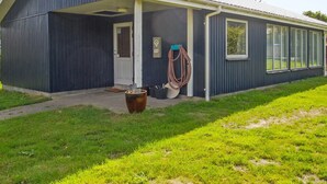A single-story building with a covered porch, a door, and a hose coiled on the side. - "Luise" - 800m from the sea by Interhome (Egernsund)