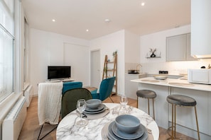 A modern kitchen with white cabinets, a marble countertop, and a built-in oven. - Leicester Square flats by Joivy (London)
