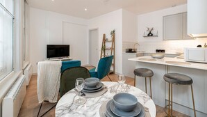 A modern kitchen with white cabinets, a marble countertop, and a built-in oven. - Leicester Square  flats by Joivy (London)