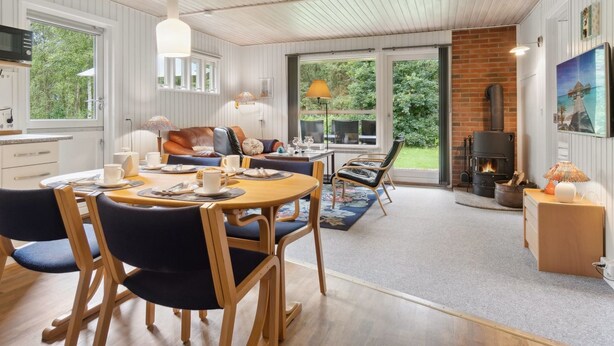 A cozy interior with a dining area, a fireplace, and a view of the outdoors. - "Alkmar" -  from the sea by Interhome (Hadsund)
