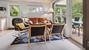 A cozy living room with a leather sofa, two chairs, a coffee table, and a large window offering a view of the outdoors. - "Alkmar" -  from the sea by Interhome (Hadsund)
