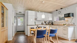 A modern kitchen with white cabinets, a wooden dining table, and blue chairs. - "Alkmar" -  from the sea by Interhome (Hadsund)