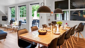 Ein moderner Essbereich mit einem Holztisch, schwarzen Stühlen und Pendelleuchten.