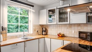 Eine moderne Küche mit weißen Schränken, einem eingebauten Backofen und einem Fenster mit Blick auf Grünflächen.
