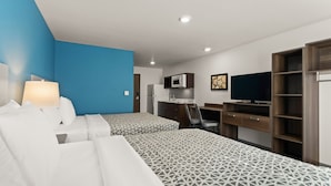 A hotel room with two beds, a desk, a TV, and a kitchenette. - WoodSpring Suites Greeley (Greeley)