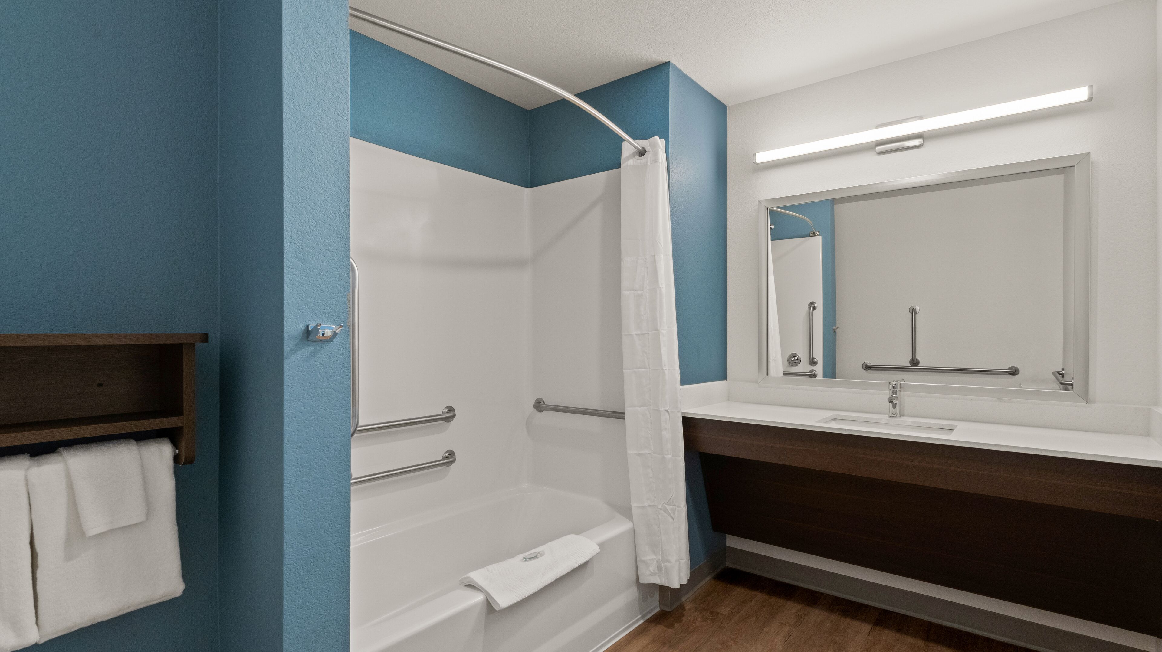 A bathroom with a shower, a bathtub, a sink with a mirror, and a towel rack.