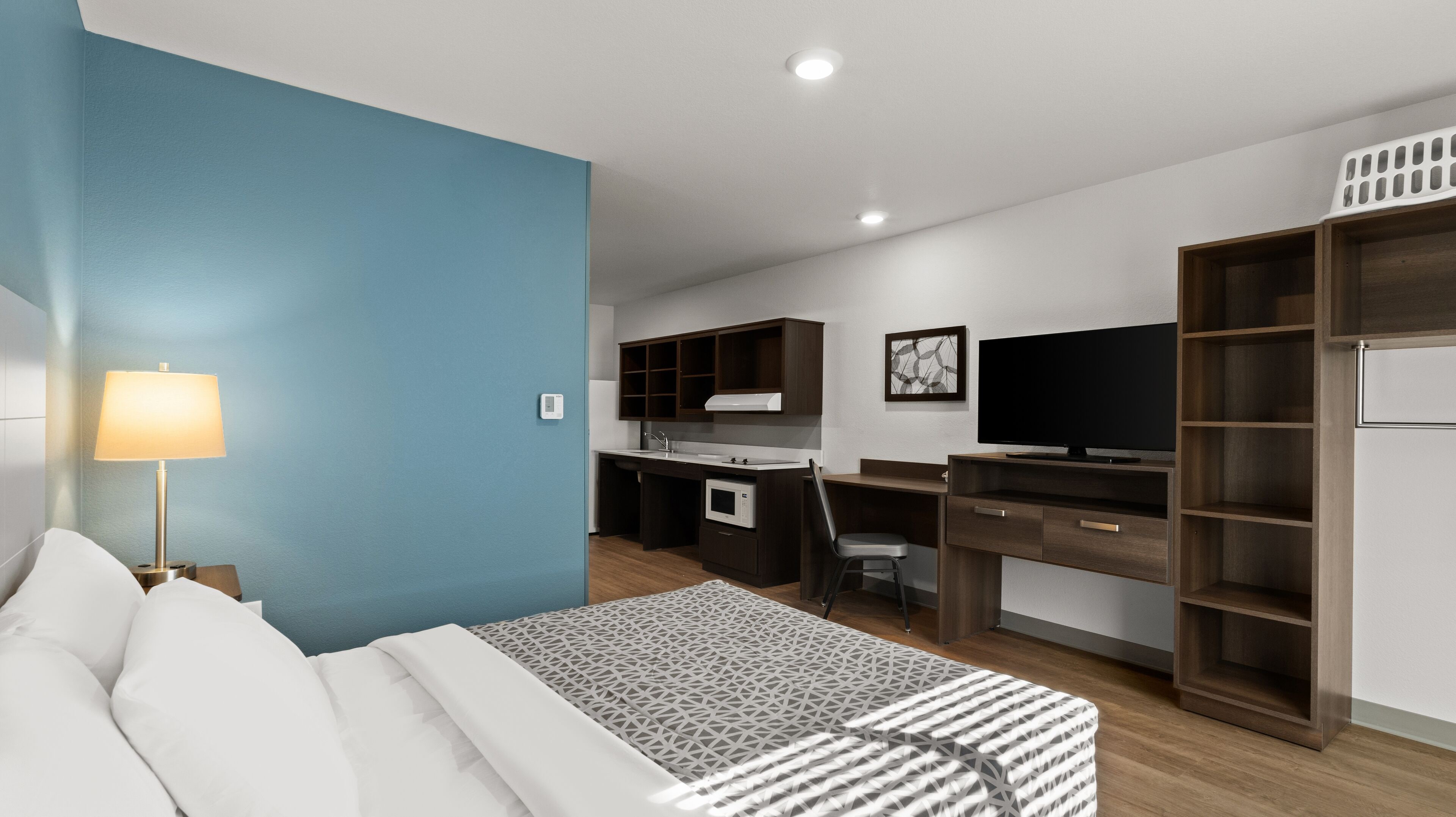 Una habitación de hotel moderna con cama, escritorio, televisor y armario.