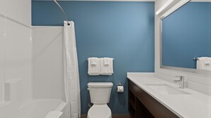 A bathroom with a shower, toilet, sink, and a mirror.
