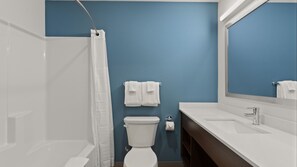 A bathroom with a shower, toilet, sink, and a mirror.