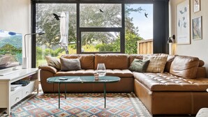 Ein gemütliches Wohnzimmer mit einem braunen Ledersofa, einem Glastisch und einem gemusterten Teppich.
