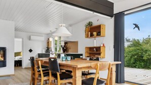 Eine moderne Küche mit einem Holzespeisetisch und -stühlen, einer hängenden Leuchte und eingebauten Regalen.