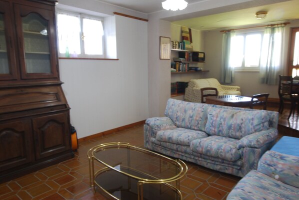 A living room with a patterned sofa, a glass coffee table, and a wooden cabinet. - Private 3-bedroom vacation home in Botontano (Botontano)
