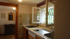 Eine Küche mit doppelter Spüle, Geschirrspüler und einem Fenster mit Metallgitter.