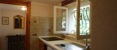 A kitchen with a double sink, a dishwasher, and a window with a metal grill.