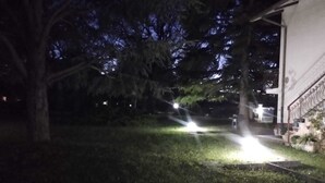 Ein beleuchteter Außenbereich mit Rasen und einem Gebäude mit geschlossenem Eingang.