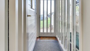 A narrow hallway with a white door, a doormat, and a view of a backyard through large windows. - "Boris" - 500m from the sea by Interhome (Aabenraa)