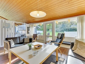 Relax in this stylish living area with a sofa, dining table, and chair, offering a view of the outdoors.