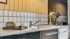 Eine Küche mit Holzwand, weiß gefliestem Fliesenspiegel, Spüle aus Edelstahl und einem Brot auf der Arbeitsfläche.