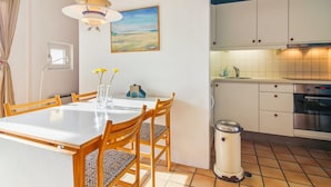 Eine moderne Küche mit weißen Schränken, einem Edelstahlbackofen und einer gefliesten Spritzschutzwand.