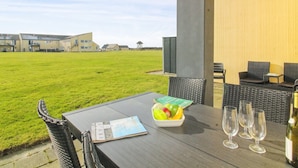 Eine Terrasse im Freien mit Esstisch, einer Obstschale und Weingläsern.
