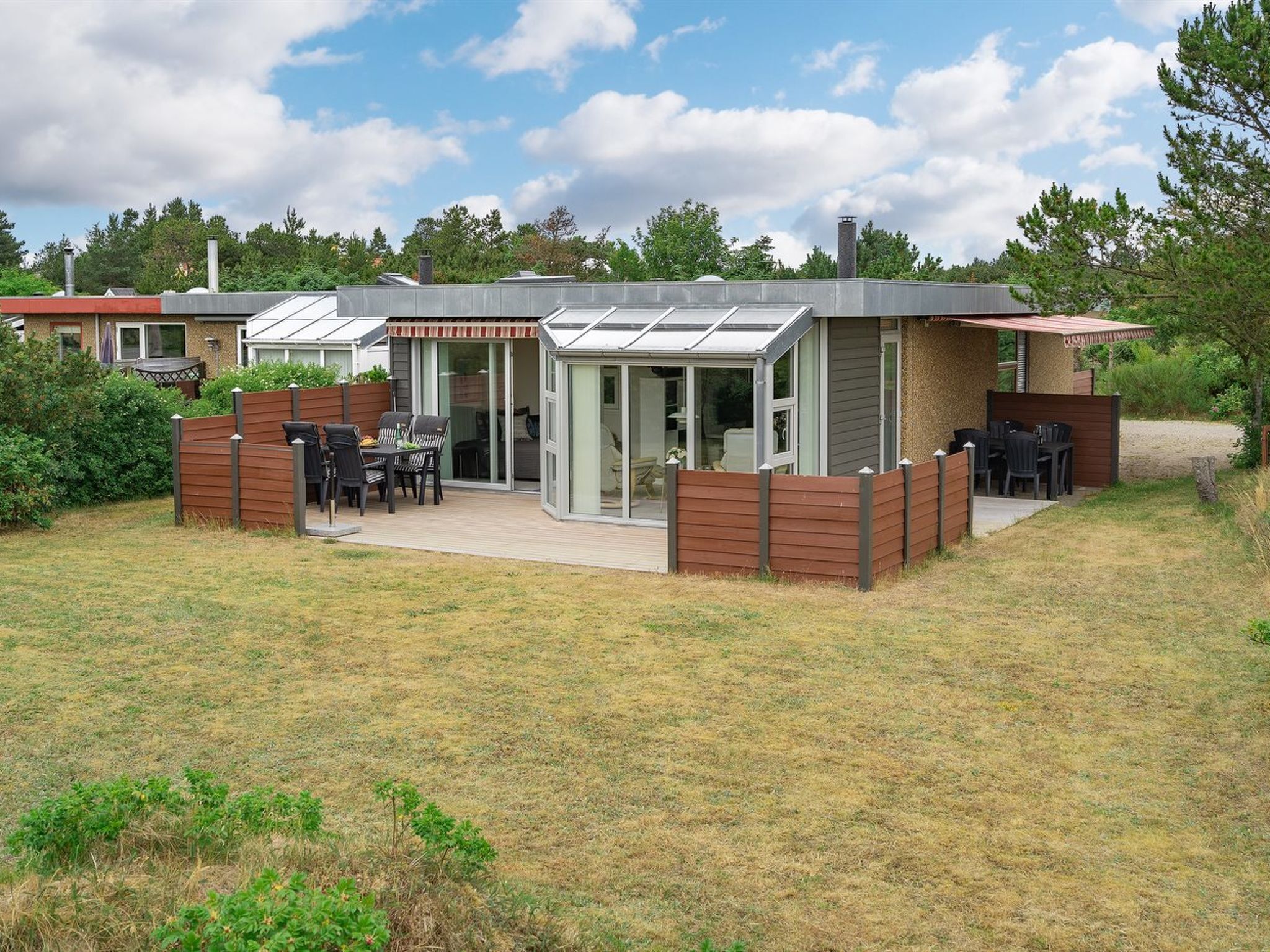 Een modern huis met een terras, een overdekte zithoek en een grote schuifpui.