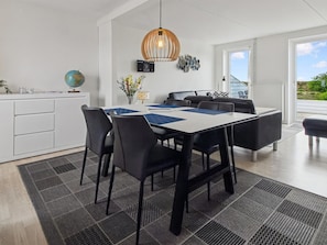 A modern dining area with a table, chairs, and a hanging light fixture.