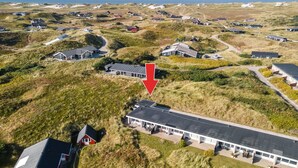 An aerial view of a coastal residential area with houses built on dunes, featuring a prominent building with a large roof and a red arrow pointing to it. - "Elizabeta" - 100m to the fjord by Interhome (Hvide Sande)