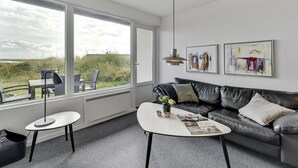 A modern living room with a large window, a black leather sofa, a white coffee table, and two side tables. - "Elizabeta" - 100m to the fjord by Interhome (Hvide Sande)