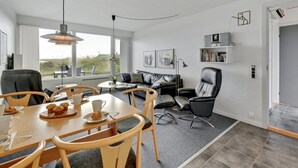 A modern living room with a dining area, featuring a sofa, chairs, a coffee table, and a bookshelf. - "Elizabeta" - 100m to the fjord by Interhome (Hvide Sande)