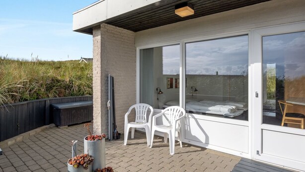 A modern outdoor patio with a bed, two white chairs, and a TV. - "Elizabeta" - 100m to the fjord by Interhome (Hvide Sande)