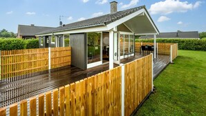 A modern house with a covered patio, a wooden deck, and a well-maintained lawn. - "Picabo" - 750m to the fjord by Interhome (Tarm)
