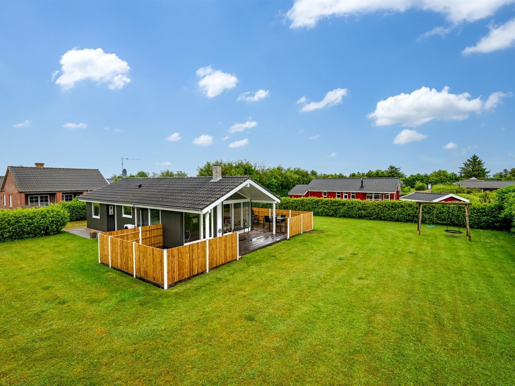 A residential property with a fenced backyard, a covered patio, and a swing set.