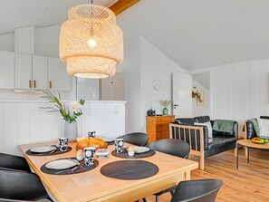 A modern kitchen with white cabinets, a dining table set with plates and cups, and a hanging light fixture.