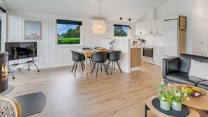 A modern kitchen with white cabinets, a dining area with a table and chairs, a black leather sofa, and a small coffee table with fruit. - "Picabo" - 750m to the fjord by Interhome (Tarm)
