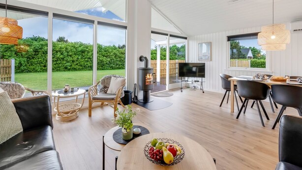 A spacious living area with a fireplace, large windows, and a dining table. - "Picabo" - 750m to the fjord by Interhome (Tarm)