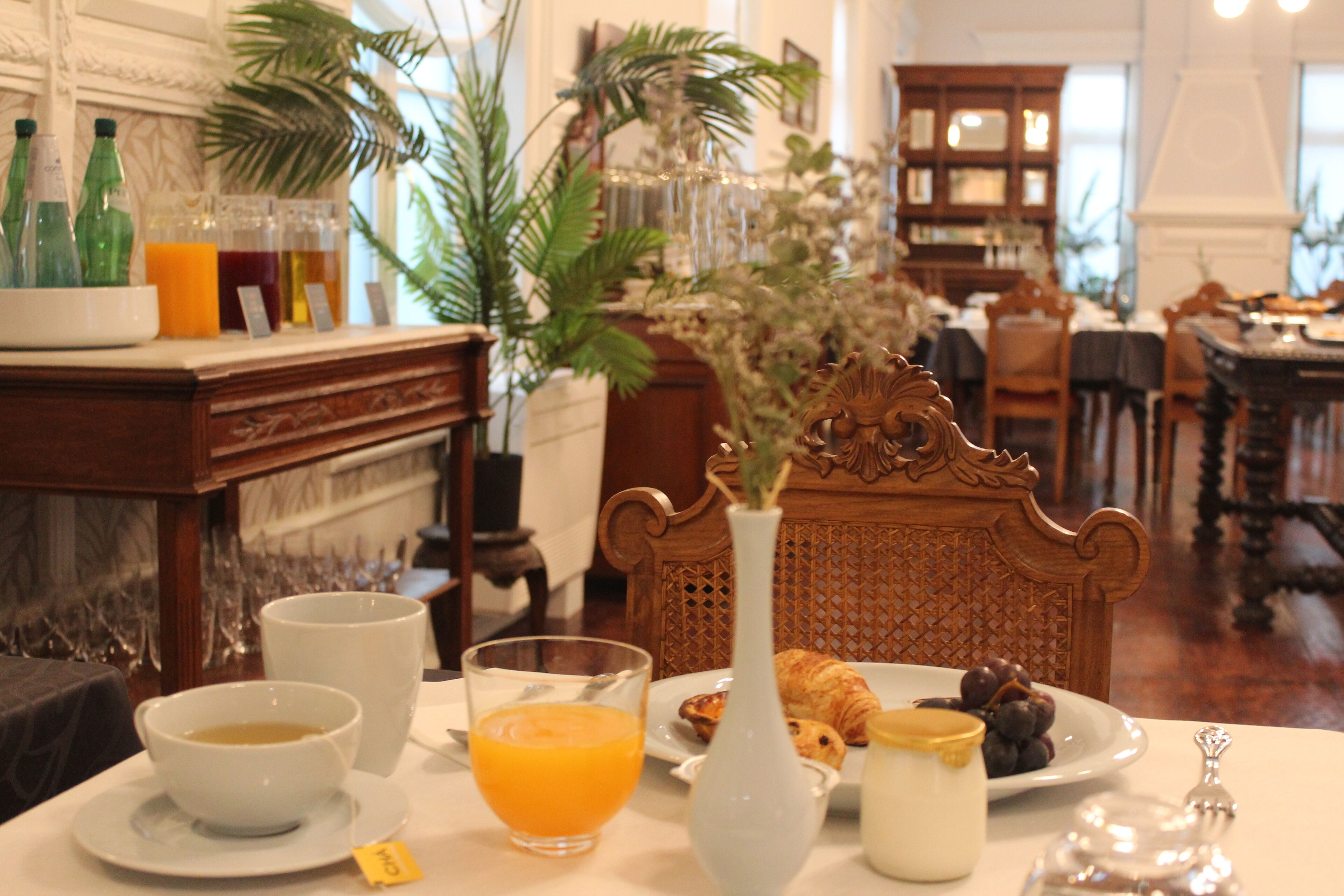 Una colazione con un tavolo, un vaso di fiori, un piatto di croissant e un bicchiere di succo d'arancia.
