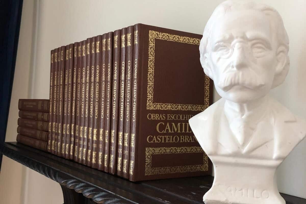 A bookshelf with a bust sculpture and a stack of books.