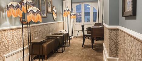 A hotel room with a carpeted floor, a dining area with a table and chairs, and a staircase with a patterned wall.