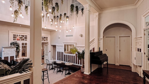 A spacious lobby with a grand piano, hanging plants, and a high ceiling with a chandelier. - GRANDE HOTEL PARIS by STAY HOTELS (Porto)