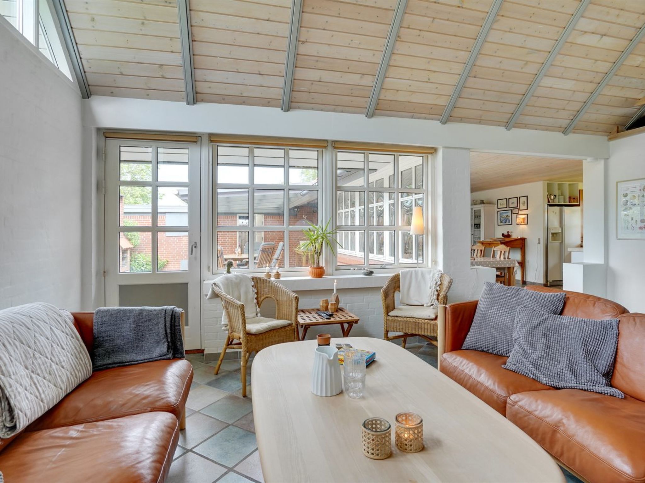 A spacious living area with a large window, a dining table, and two leather sofas.