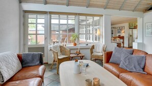 A spacious living area with a large window, a dining table, and two leather sofas. - "Radojka" - 75m from the sea by Interhome (Otterup)