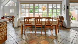 A dining area with a wooden table and chairs, large windows, and a view of the outdoors. - "Radojka" - 75m from the sea by Interhome (Otterup)